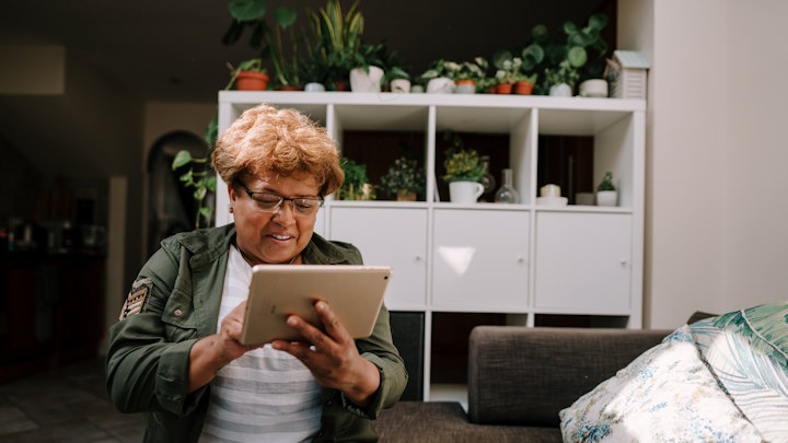 An older Black woman using an iPad at home.