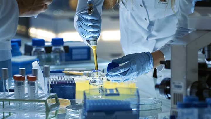 A researcher using a pipette to transfer liquid.