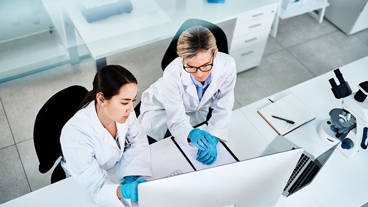 Two researchers are using a computer in the lab.