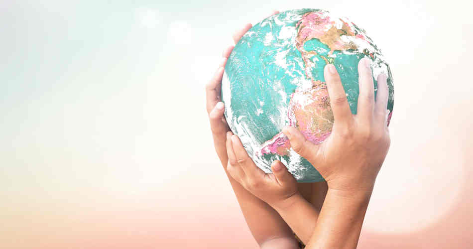Children's hands holding up a model of Earth.