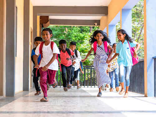 Image: South Asian children running outside a school.