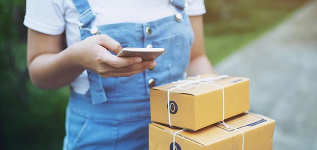 A person using a smartphone to record the delivery of two boxes.