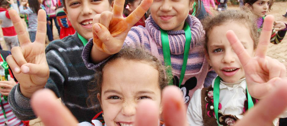 Children making peace signs.
