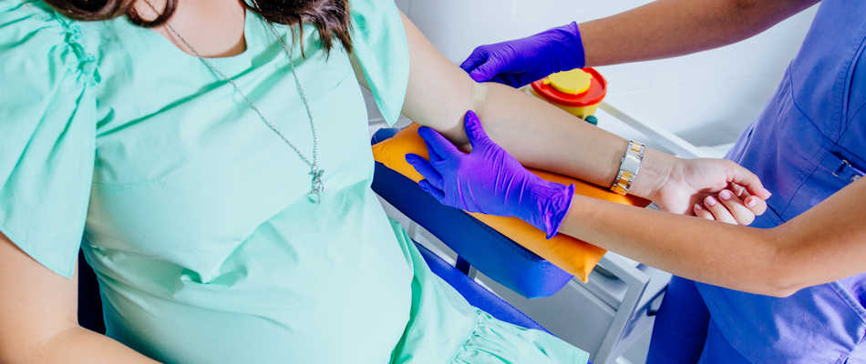 A pregnant woman has a plaster applied to her arm after a blood test.