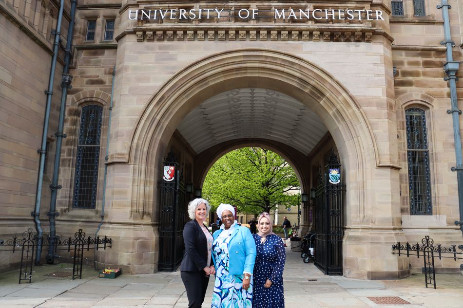 Suzanne Johnson, Ncazelo Ncube and Binish Khatoon standing in front of the University of Manchester archway on campus.