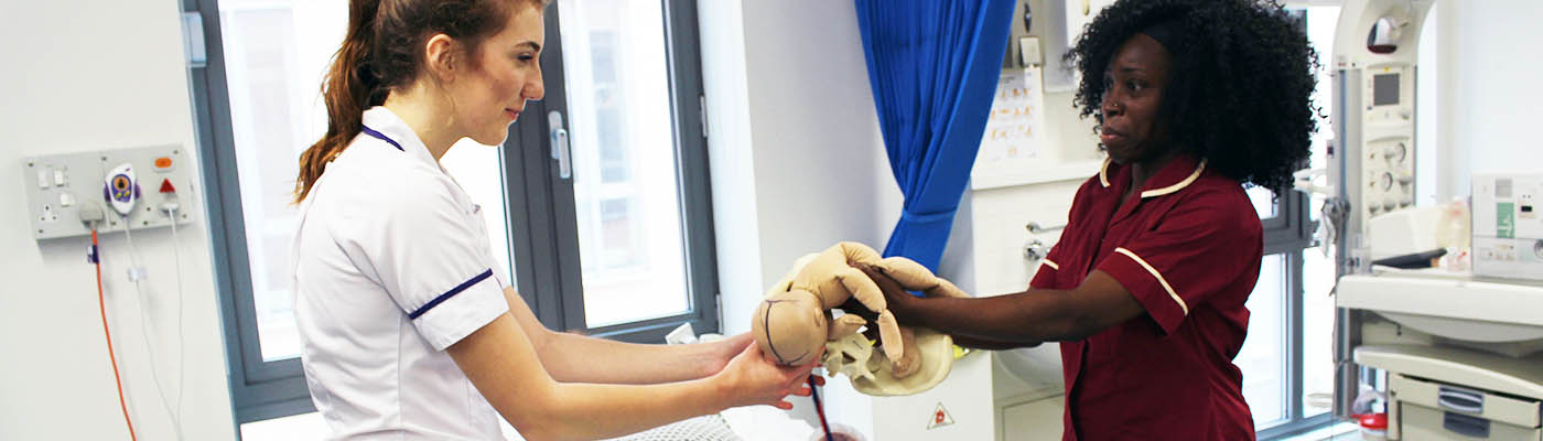 A student midwife learns how to hold a newborn baby in the clinical skills suite.