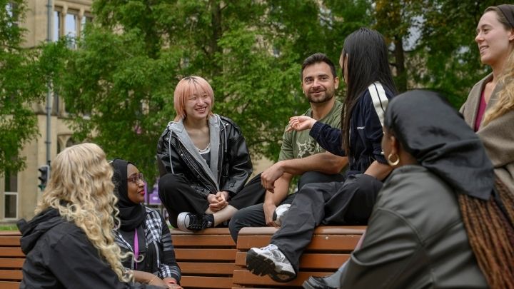 Postgraduate researchers sat on a bench chatting and smiling