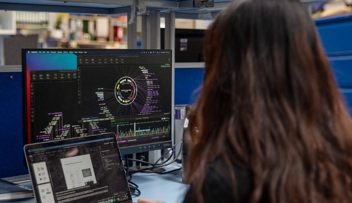 A postgraduate researcher looking at computer screens in their write-up area.