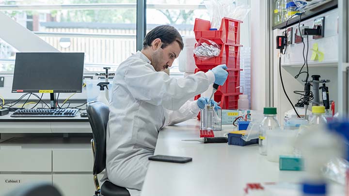 A postgraduate researcher using a pipette.