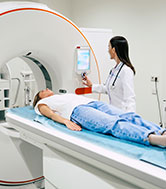  A person going into an MRI machine with a doctor standing by.