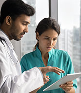 Two doctors working together on a digital tablet.