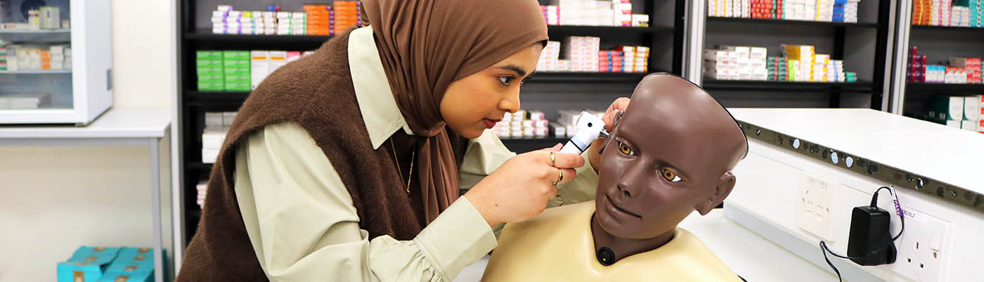 A pharmacy student practicing an ear examination in the clinical skills suite.