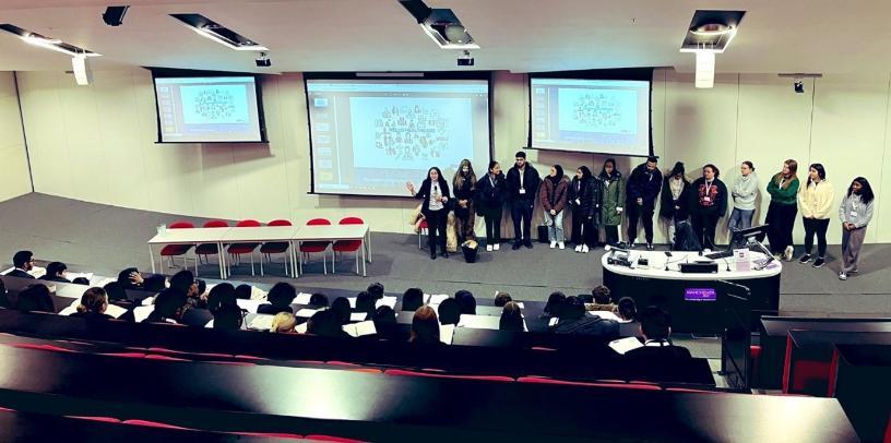 Medical students giving a talk to school pupils in a lecture room.