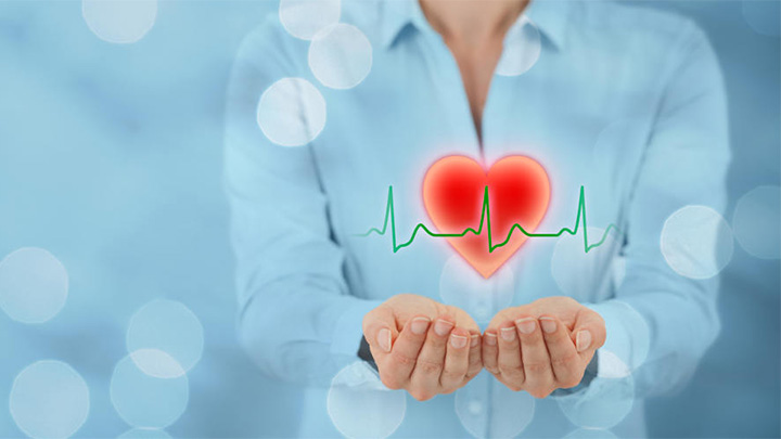 A woman holding a graphic of a heart in her hands.