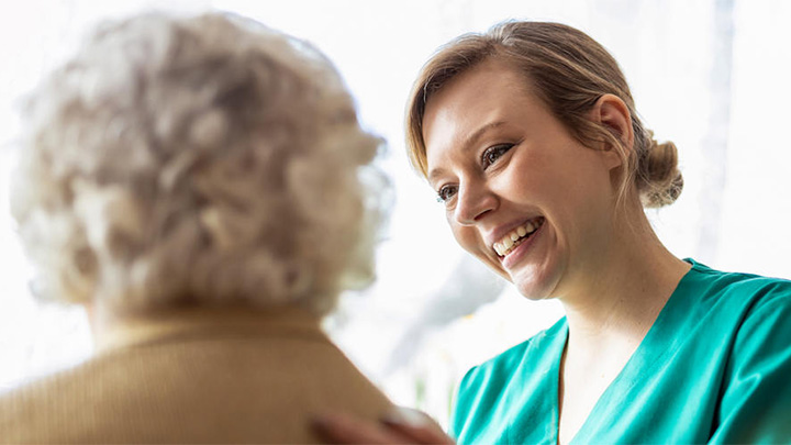 A health worker talking with an older woman.