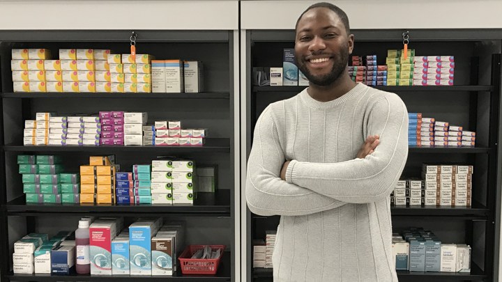 A student standing in front of shelves of pharmaceutical supplies.