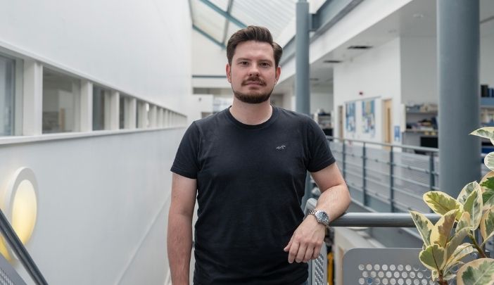 Male postgraduate researcher in black t-shirt looking at camera