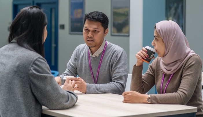 A group of three students chatting at a table