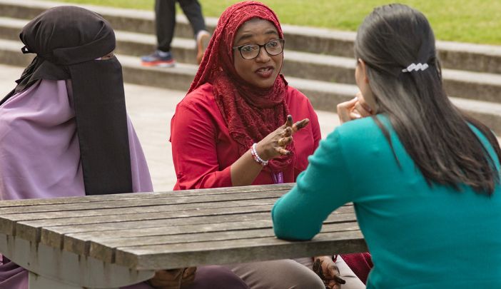 A group of three students at a picnic table deep in conversation.