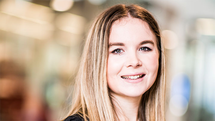 Portrait style photo of a woman with light hair against a bright background.