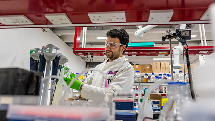 Researcher in a lab looking at an object in his hands.