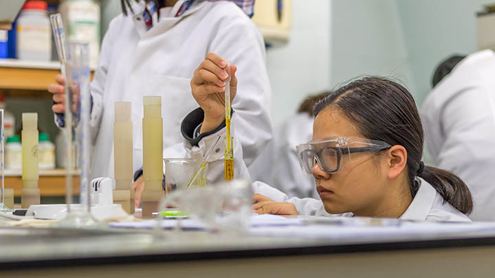 Researcher in a lab holding a pipette.