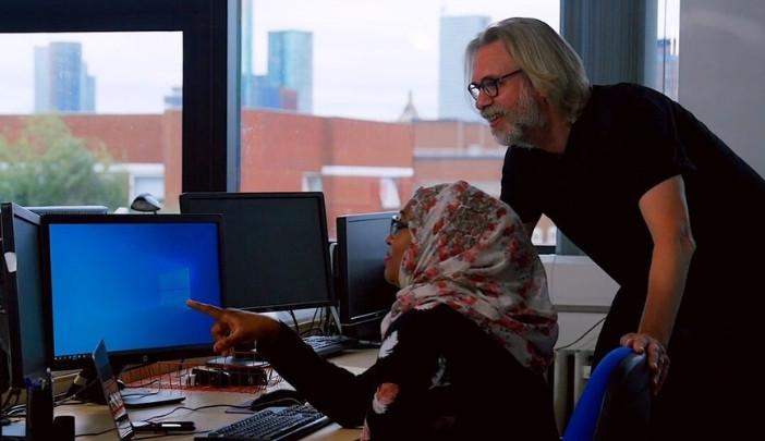 A supervisor and postgraduate researcher looking at a screen smiling