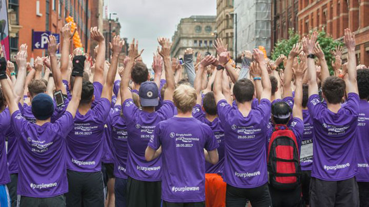 A group of Manchester students in matching purple t-shirts taking part in a run through Manchester.