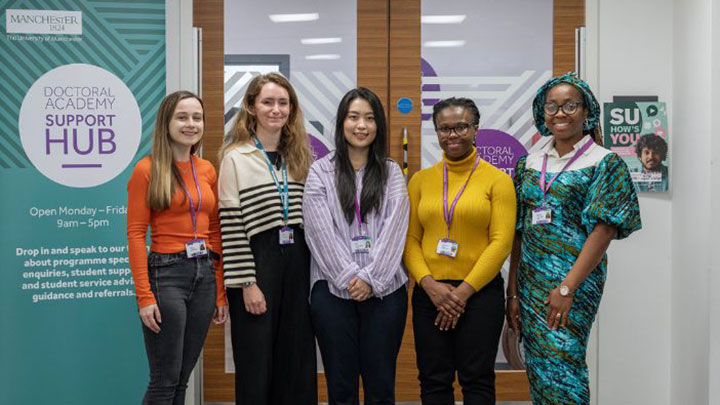 A group of postgraduate researchers standing in front of the PGR student support hub. 