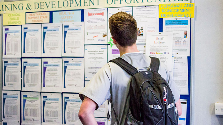 Postgraduate student looking at a board of development opportunities in a teaching hospital.