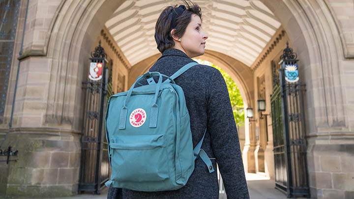 Student with backpack stood in front of campus building