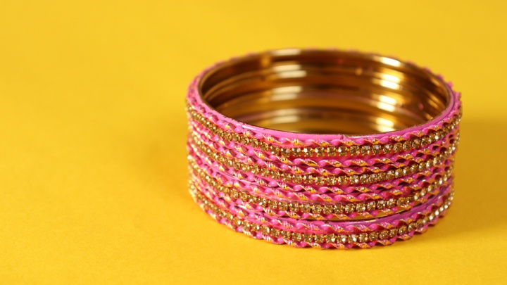 A stack of pink bangles on a yellow surface.